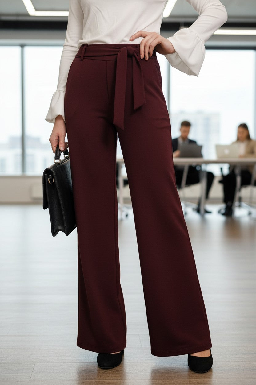 Pantaloni office evazați de damă cu cordon, bordo – vedere din față, cu o geantă