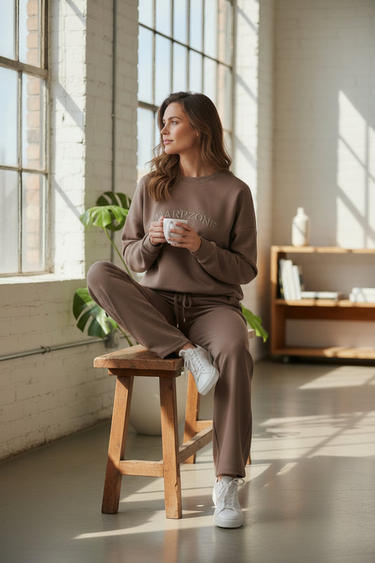Set trening de damă cu pantaloni drepți, grej – așezată pe un scaun